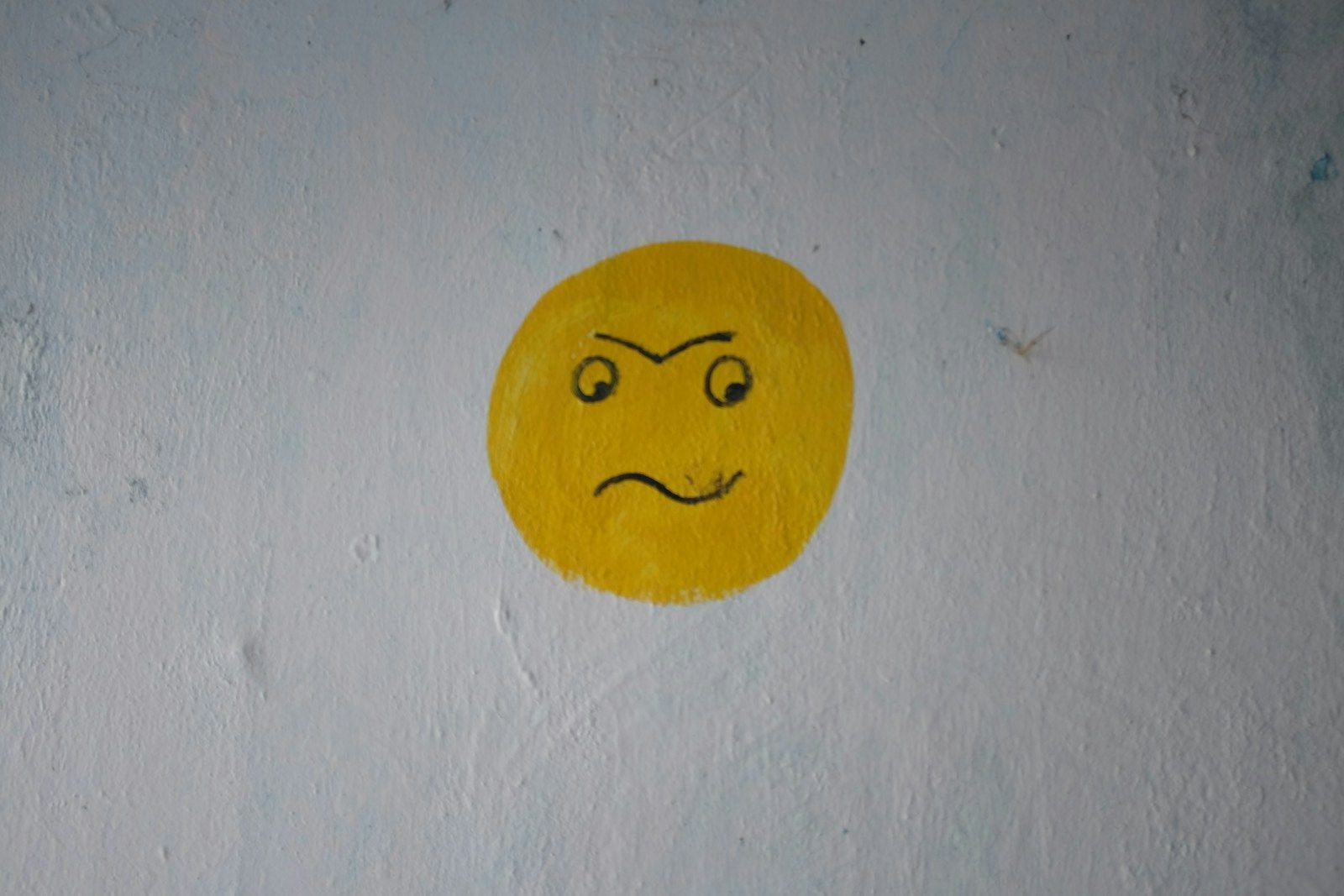 a yellow smiley face painted on a white wall